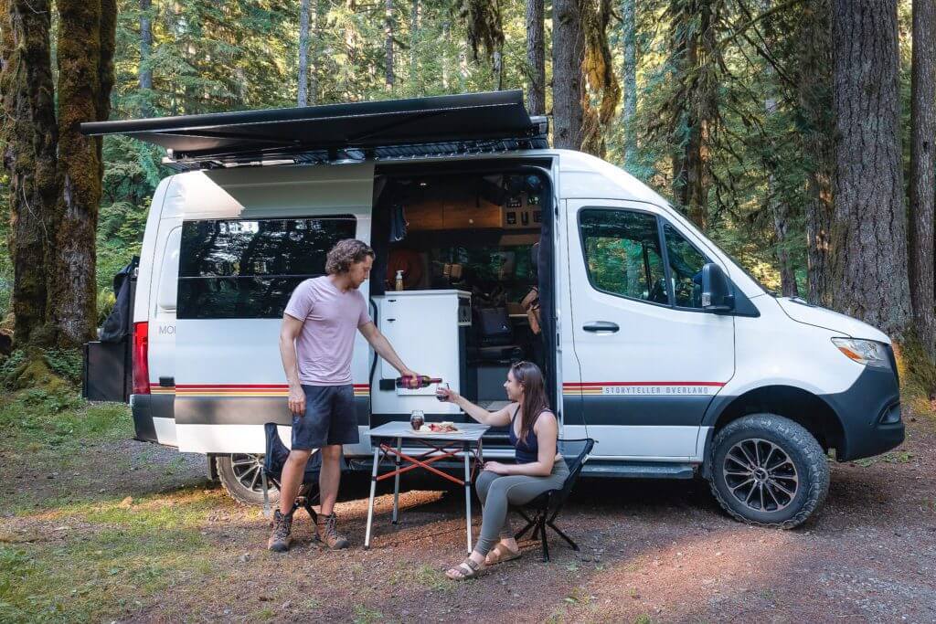 Man pouring a woman a glass of wine outside of a camper van rental in Seattle
