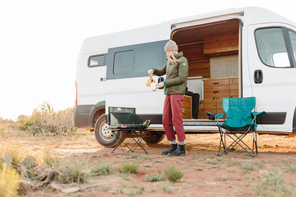 Woman pouring coffee outside of a camper van rental