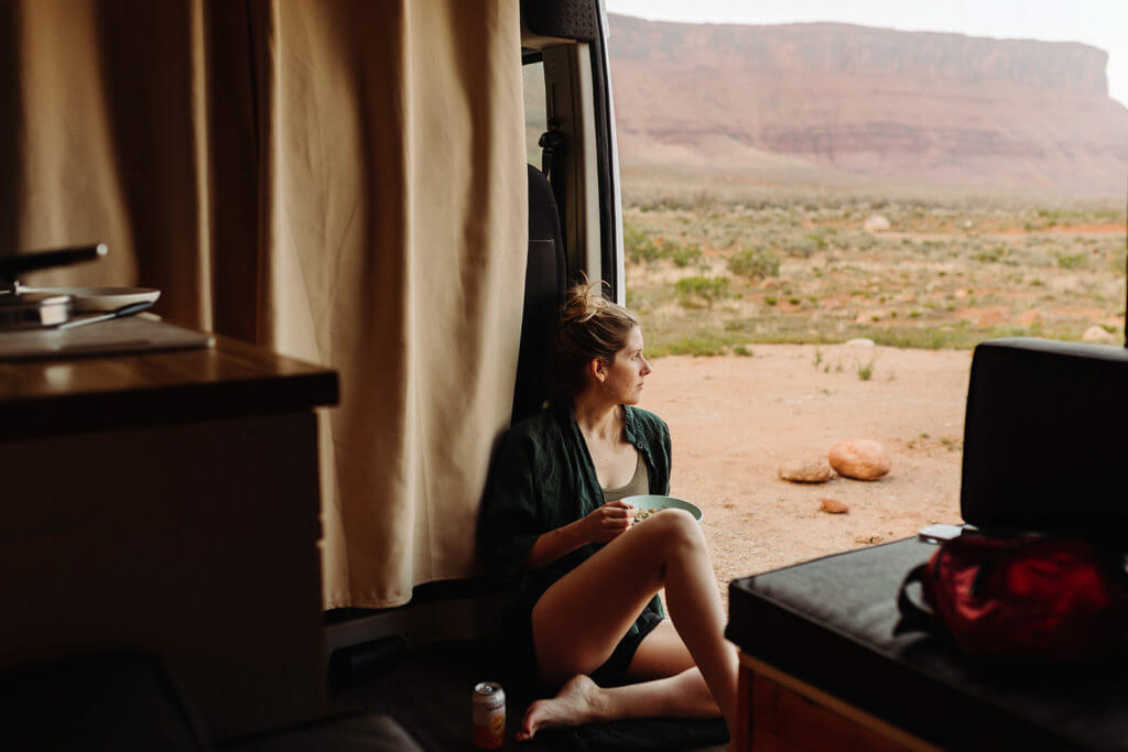 Woman gazing out the sliding door of camper van rental into the desert