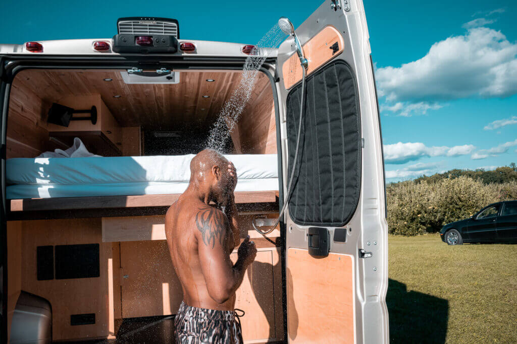 Man showering out of the back of a camper van rental